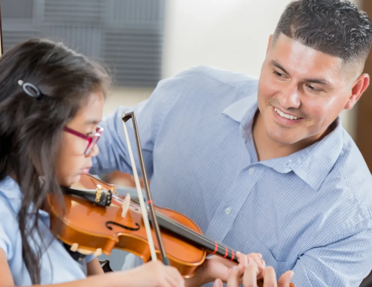A close-up of a young student's hands holding a stringed instrument