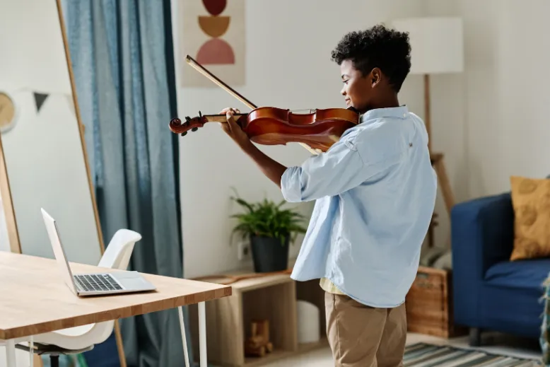 homeschooled child engaged in an online music lesson, showing the child smiling and interacting with their instructor via a computer or tablet. child engaged in an online music lesson