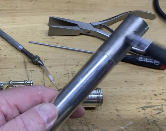 Close-up of a hand applying graphite to a flute joint using a penci